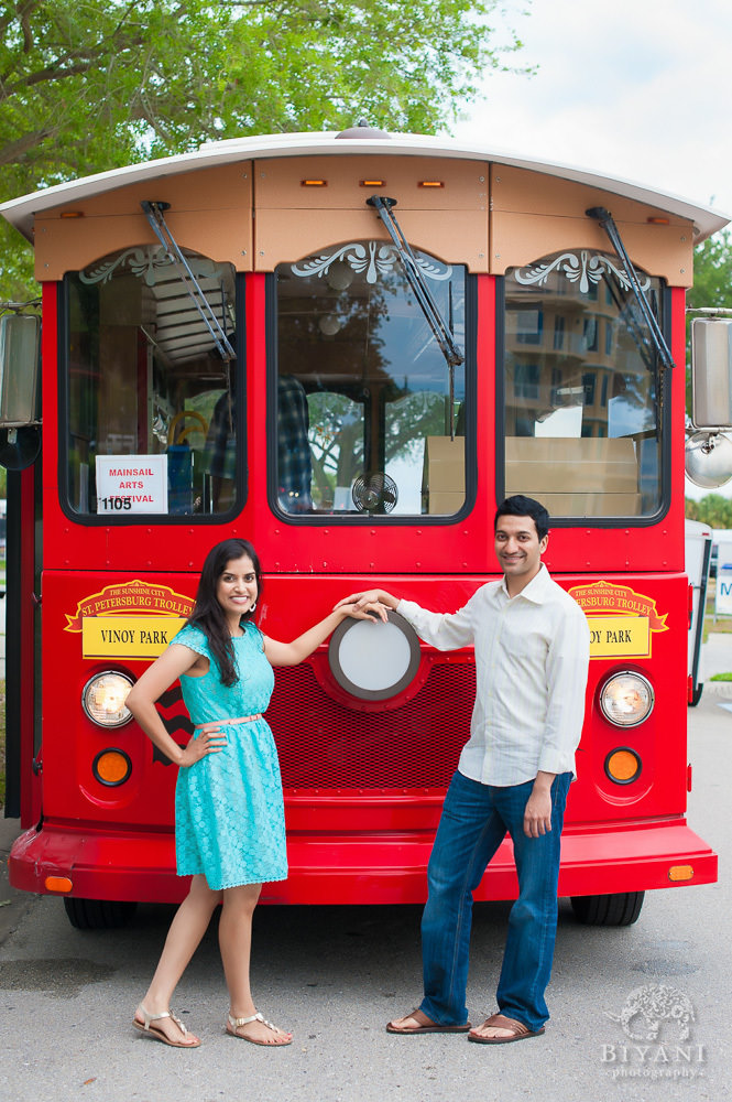 Engaged Indian Couple posing in-front of a red bus in Downtown Tampa for their Indian Engagement photos