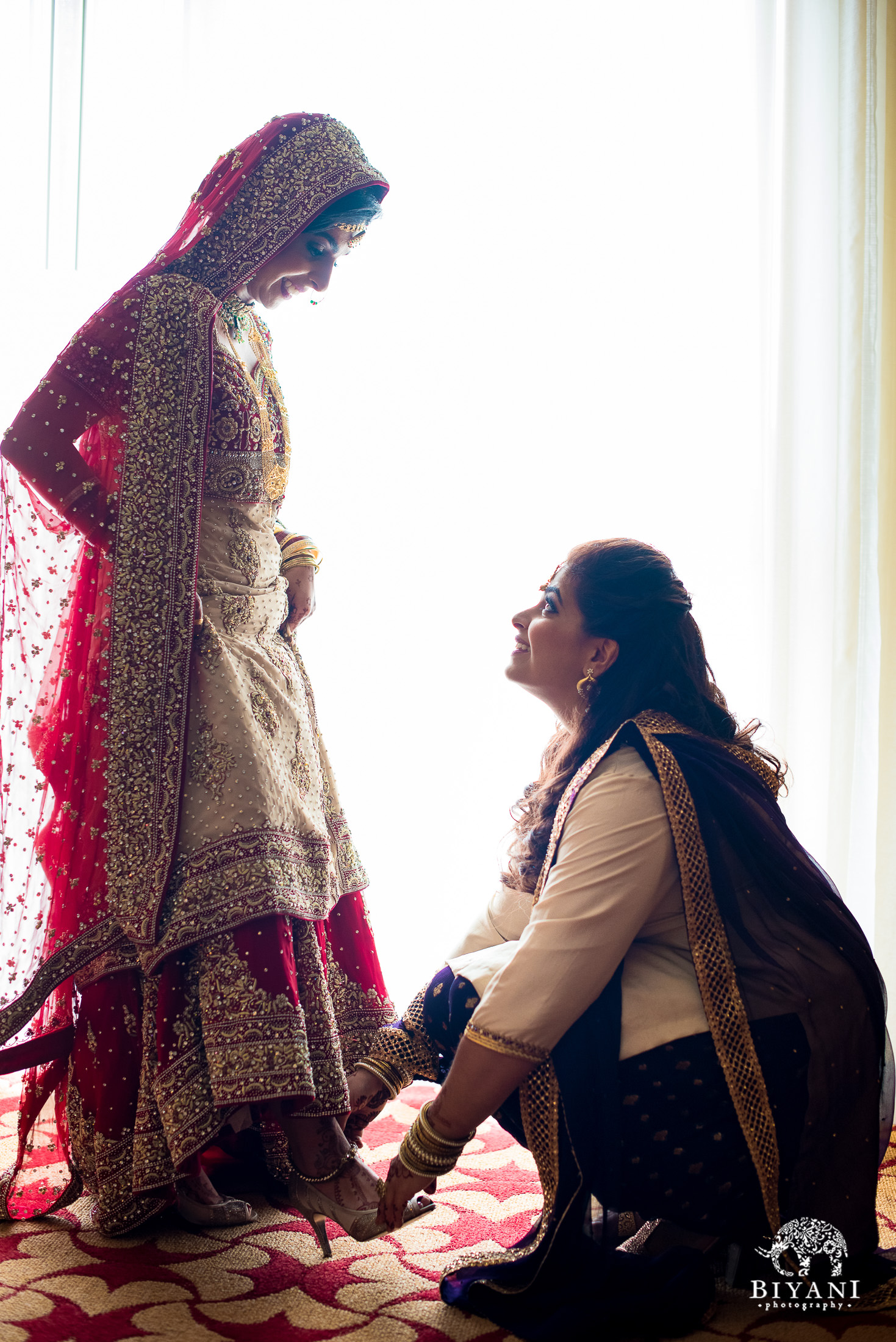 Indian bride and her sister helping her get ready before her wedding ceremony 