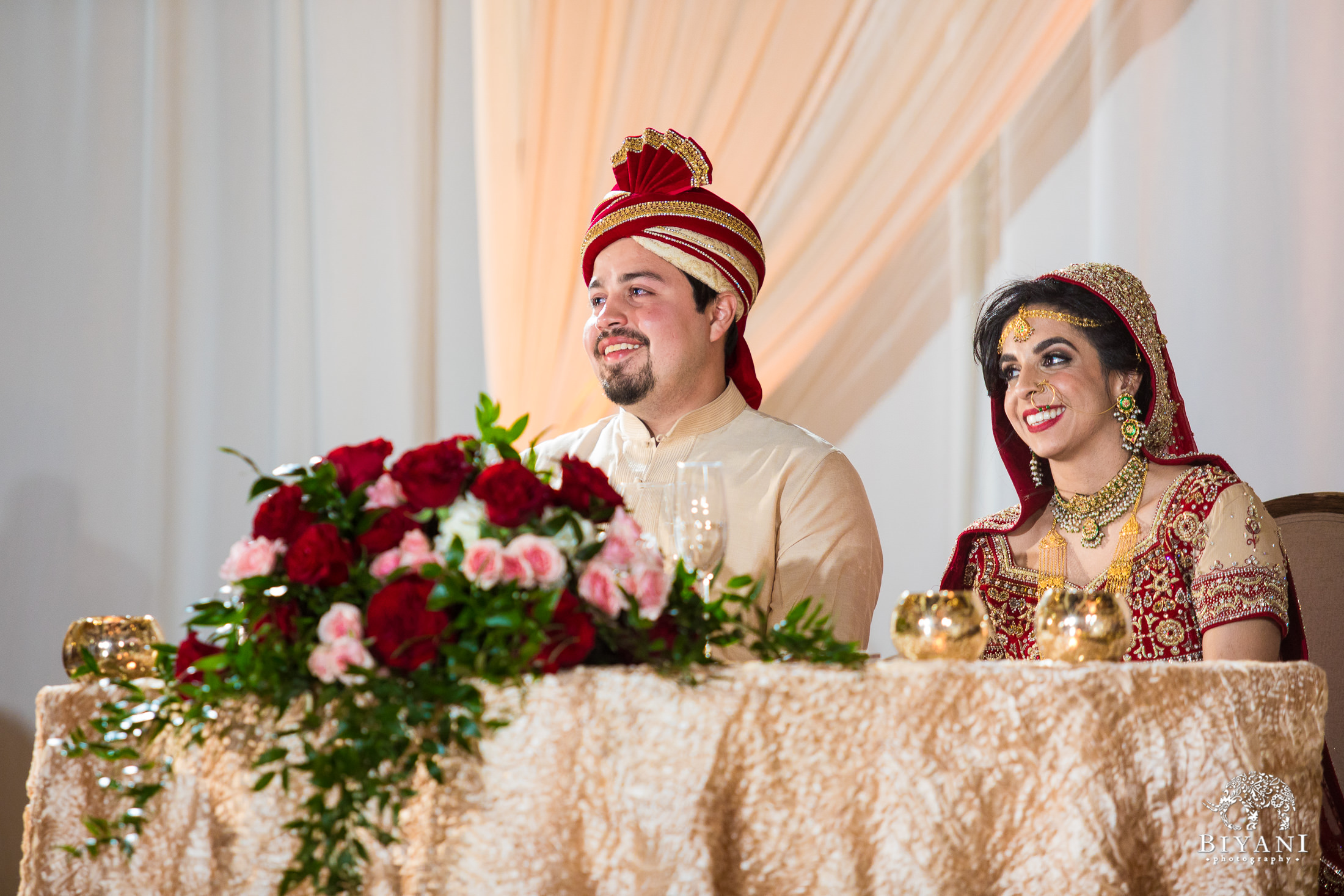 Indian Fusion bride and groom listening to speeches during the reception party