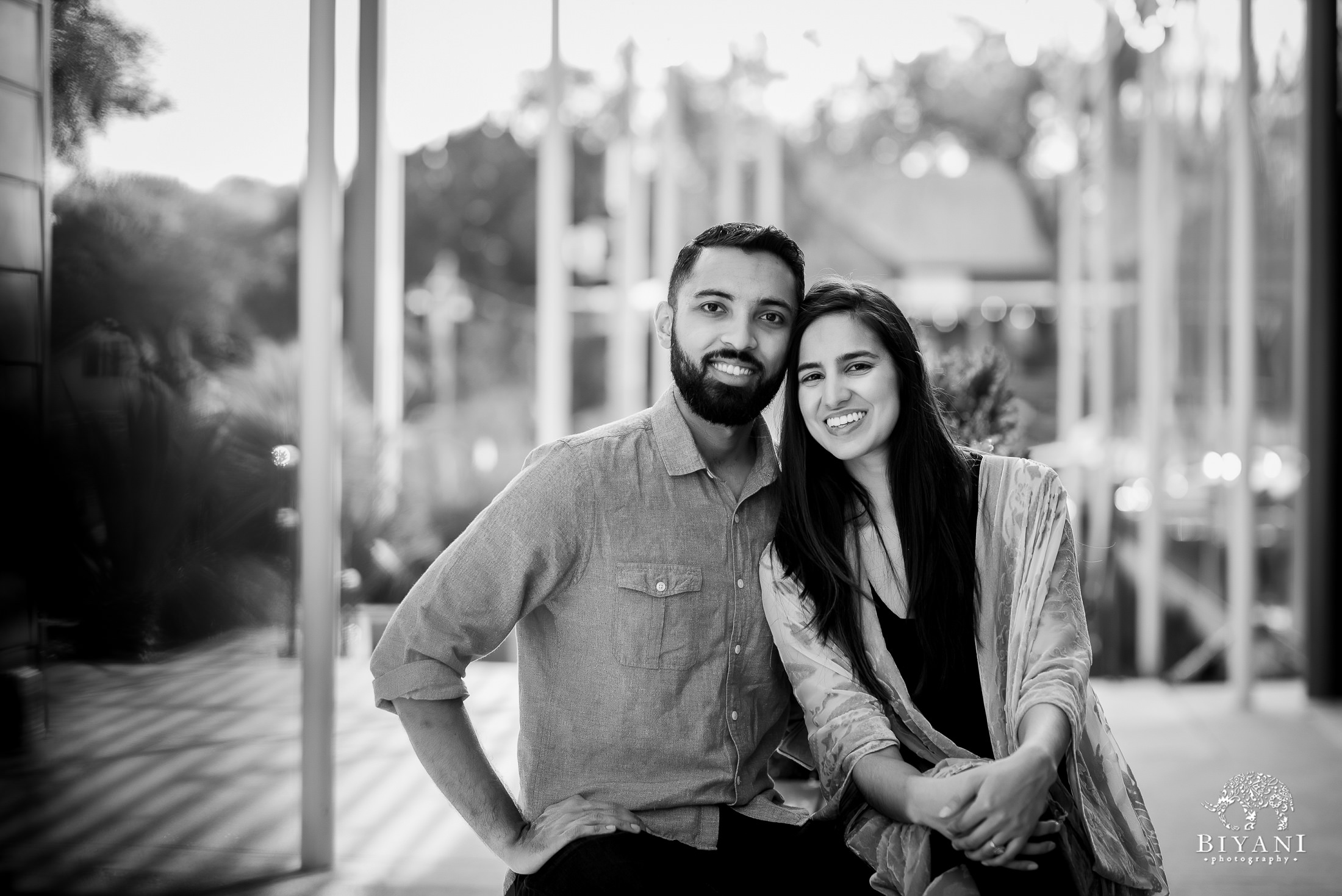 An Indian couple sitting together in South Congress Austin, Tx. for their engagement photo shoot