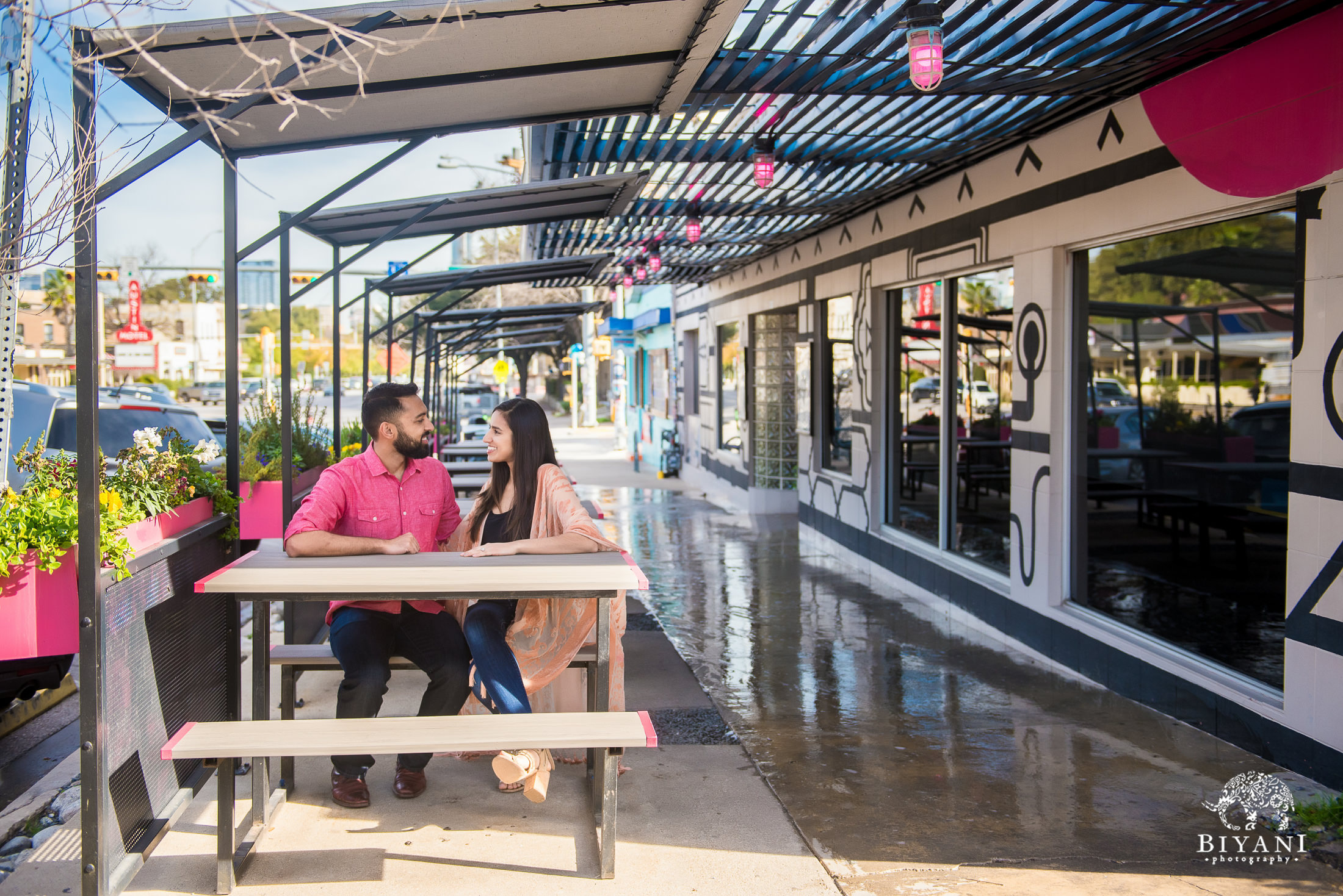 Indian couple sitting down on a picnic bench during their engagement photo shoot in South Congress Austin, Tx.