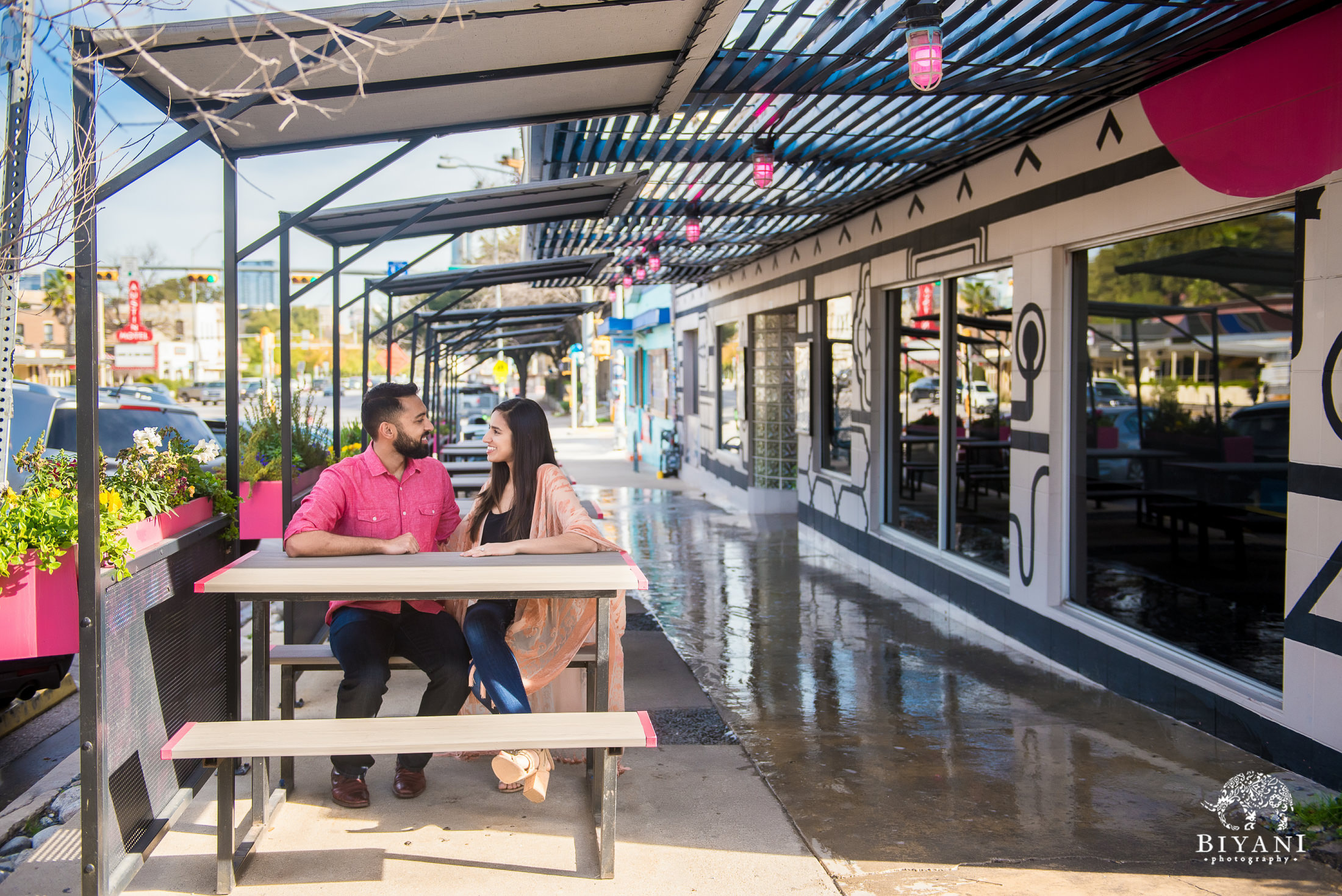 Indian couple sitting down on a picnic bench during their engagement photo shoot in South Congress Austin, Tx. 