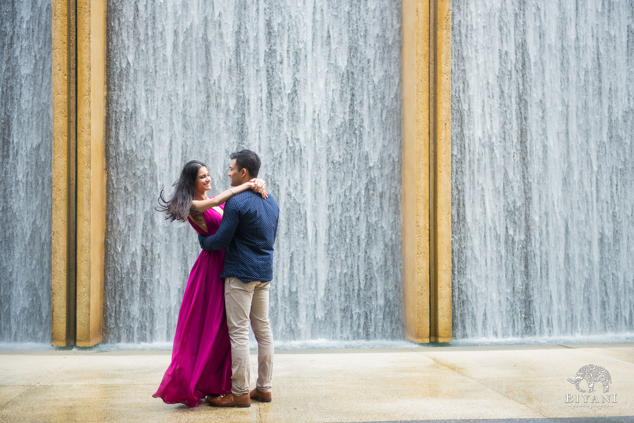 couple hugging in front of water wall