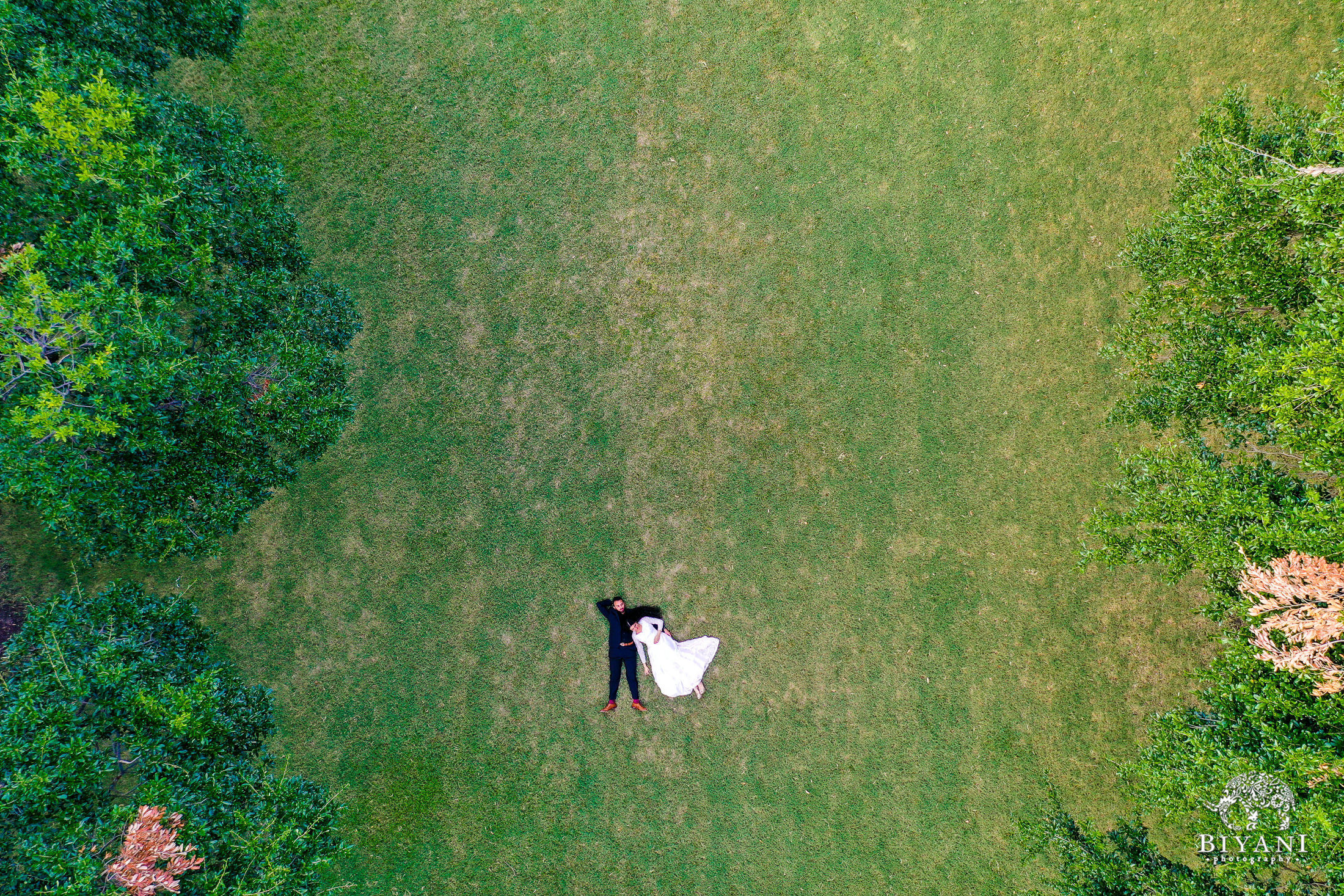 drone photography of couple laying on grass together