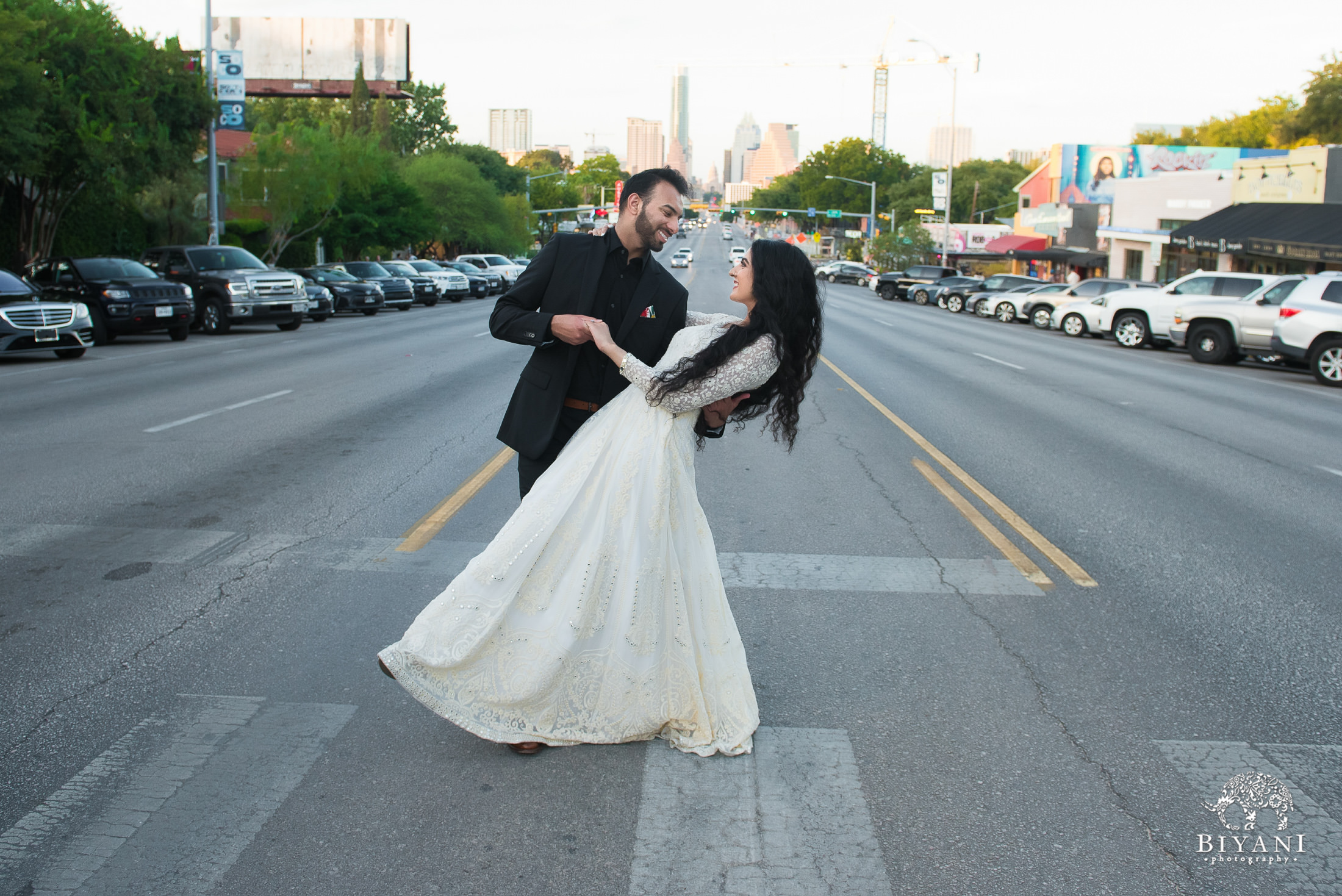 bride being dipped by groom in the middle of intersection with Austin city Capital in background