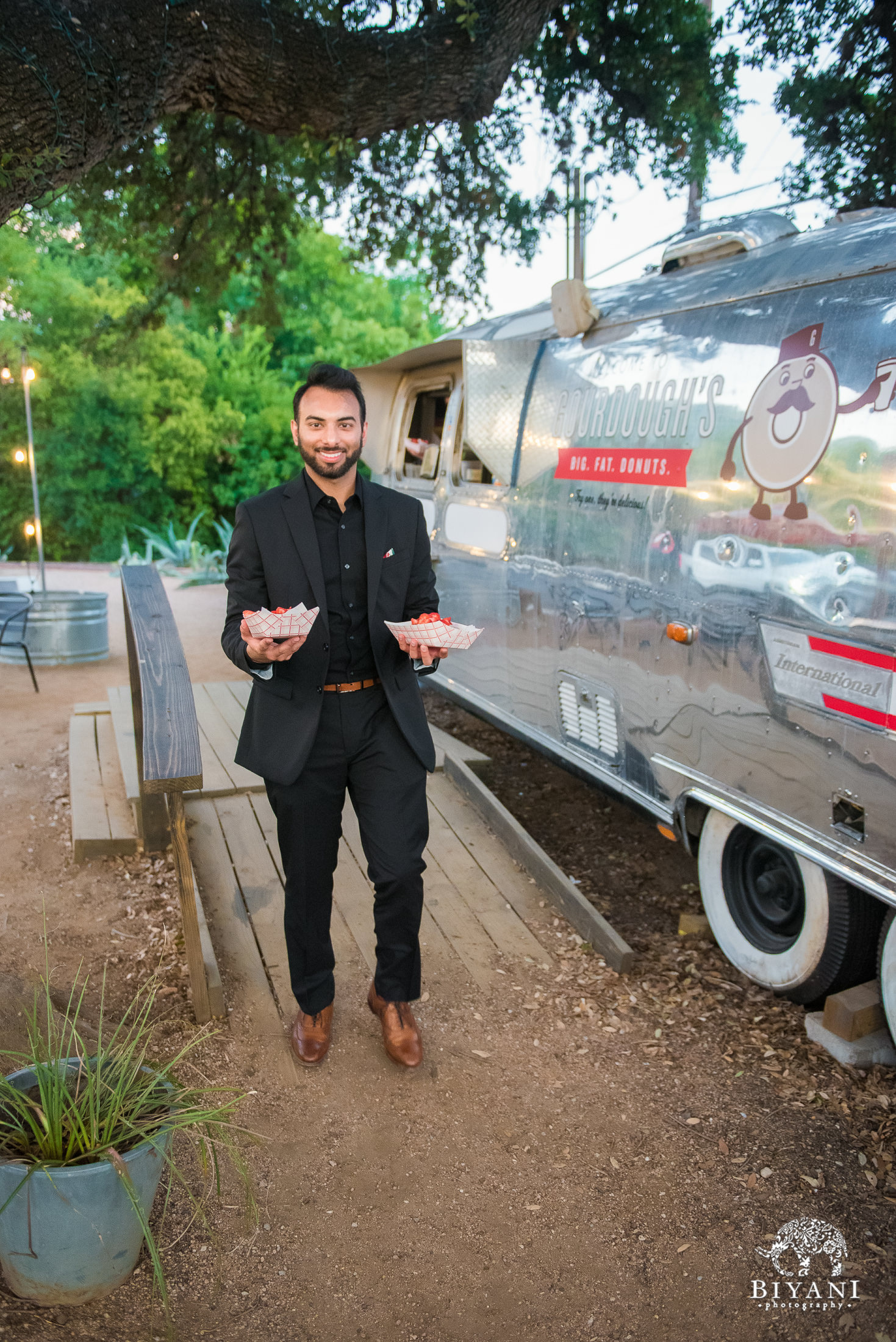 Groom carrying two orders of Gourdough's Big. Fat. Donuts. in Austin Texas