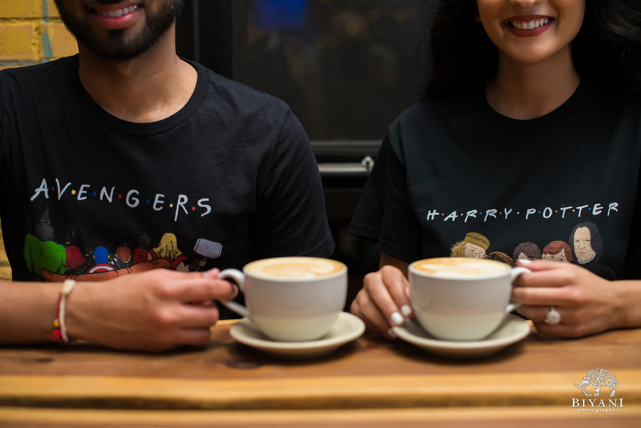 couple enjoying cappuccinos together at a coffee shop wearing Avengers and Harry Potter t-shirts 