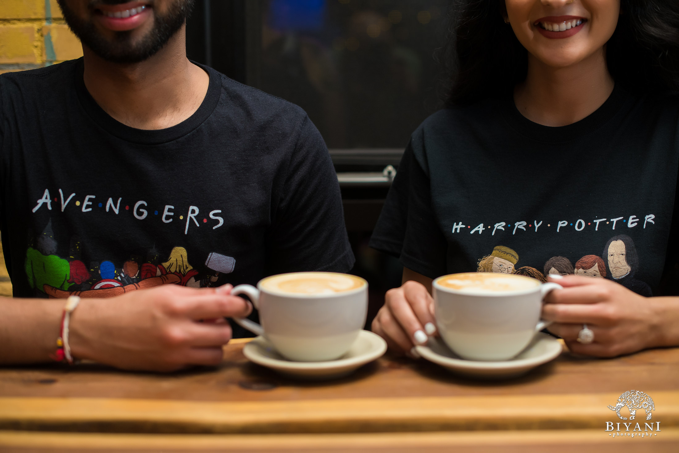 couple enjoying cappuccinos together at a coffee shop wearing Avengers and Harry Potter t-shirts