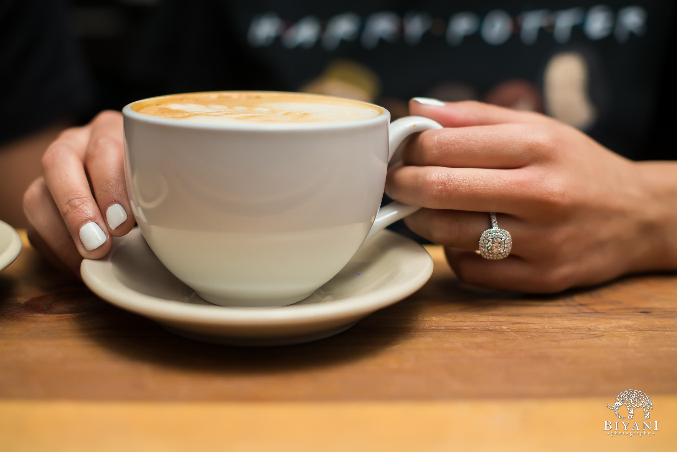 bride holding her cappuccino cup with engagement ring on her finger